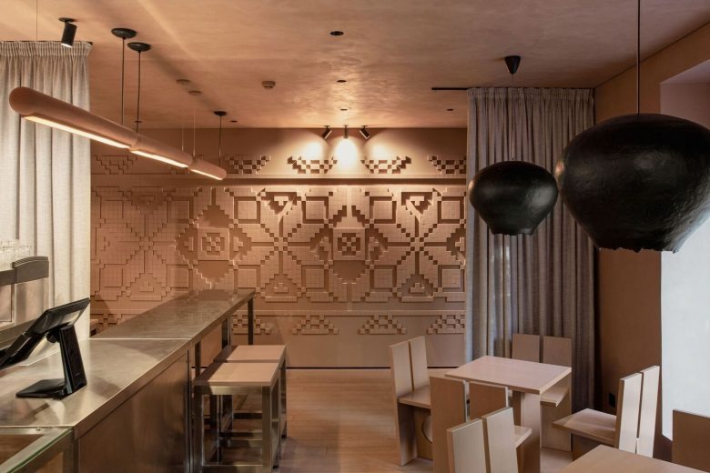 Интерьер кофейни с барной стойкой и настенным орнаментом Kofan Coffee Shop