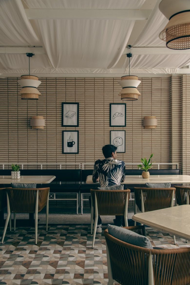 Интерьер кофейни с гостем за столом и настенными иллюстрациями Sidewalk Bakehouse and Cafe