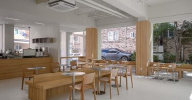 Общий вид зала с большими окнами и деревянной мебелью Prompt Café