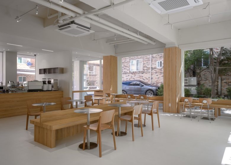Общий вид зала с большими окнами и деревянной мебелью Prompt Café