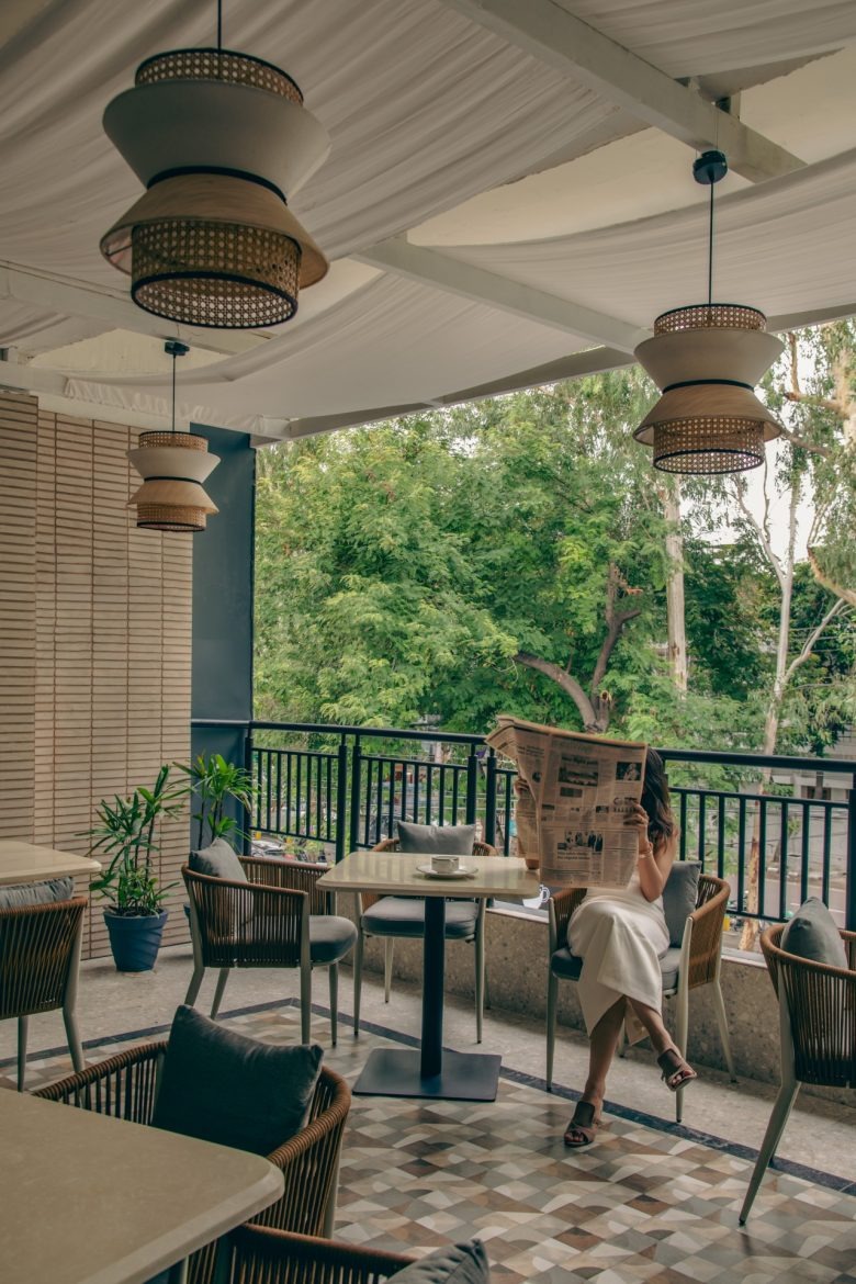 Терраса с посадочными местами и гостем с газетой Sidewalk Bakehouse and Cafe