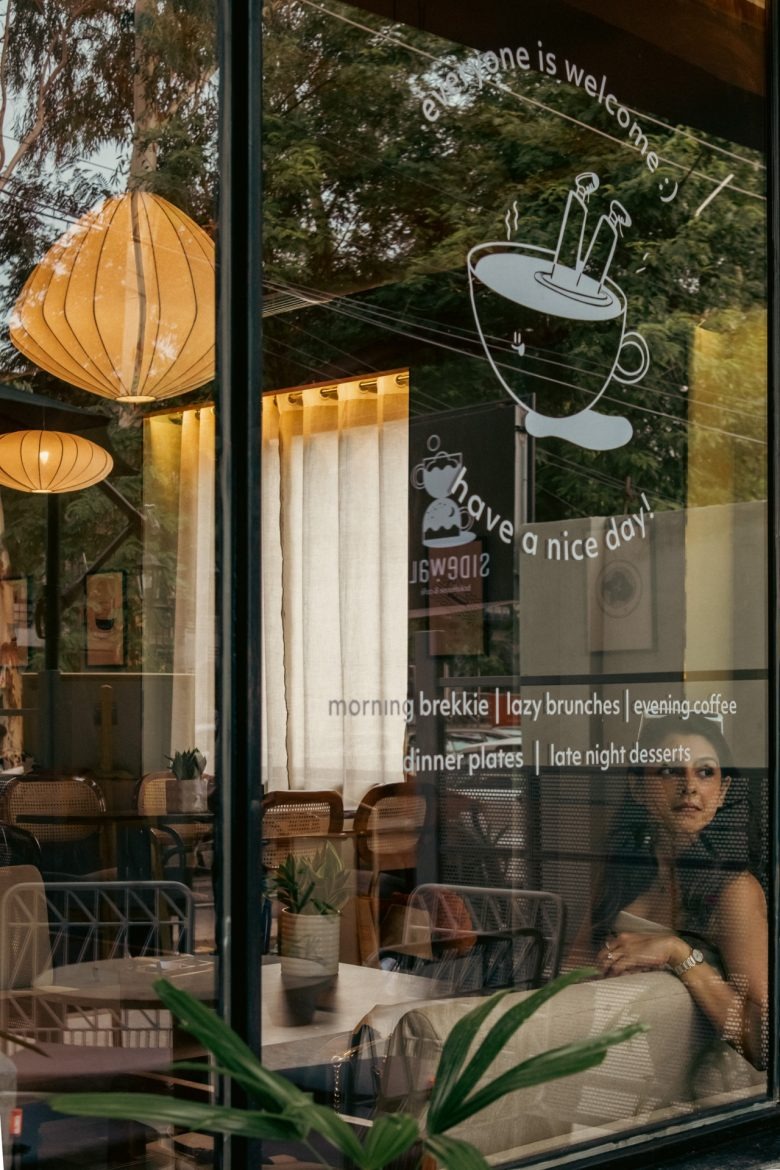 Вид через стекло с графикой и интерьером кафе Sidewalk Bakehouse and Cafe