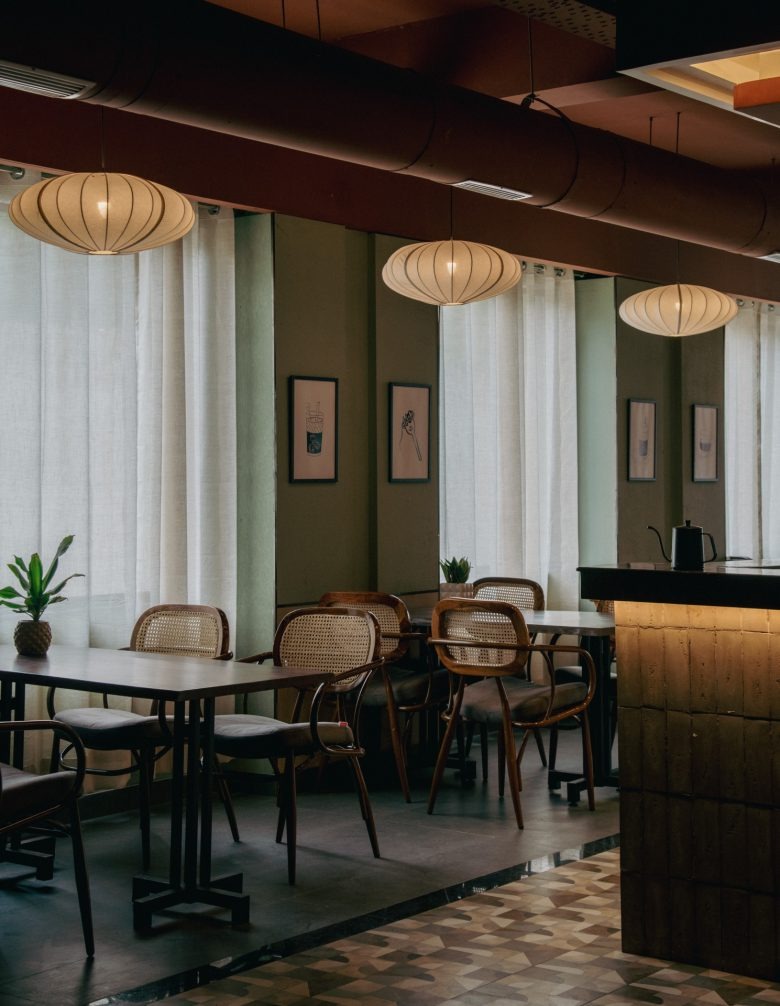 Зона у окна со столами и мягким освещением Sidewalk Bakehouse and Cafe