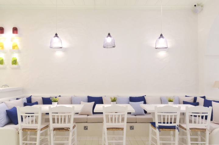 Светлый диван с подушками синих оттенков в интерьере ресторана в средиземноморском стиле
