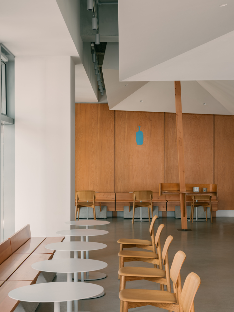 железные столики вдоль окна Blue Bottle Coffee at West Bund